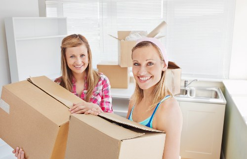 Movers carrying household items through a flat building entrance
