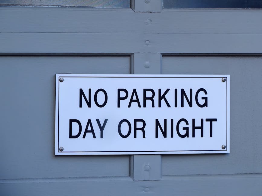 A green and white parking restriction sign mounted on a metal pole outdoors, indicating a two-hour parking limit from 8 am to 8 pm, with exemptions on Sundays. The sign features clear text and symbols